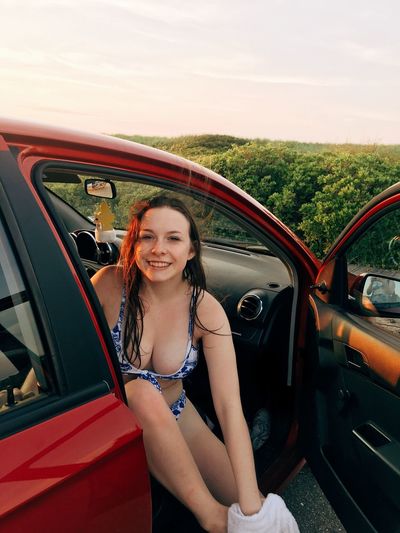 Portrait of smiling beautiful woman wearing bikini while sitting in car