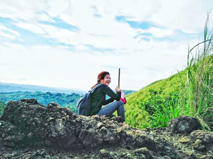 Full length of woman sitting on mountain against sky