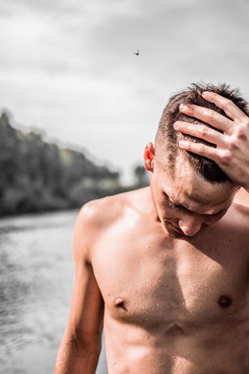 Portrait of shirtless young man against sky