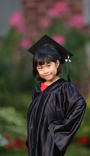 Portrait of girl wearing graduation gown while standing outdoors