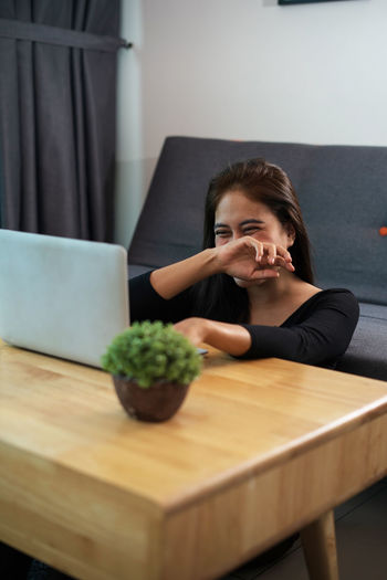 Portrait of young woman using phone while sitting on table
