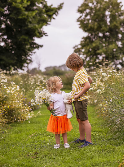 Full length of girl and boy with flowers 