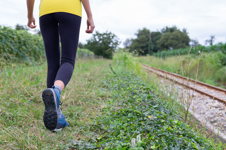Low section of woman walking on field