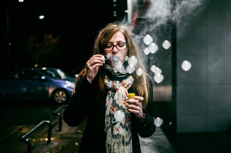 Woman blowing bubbles at night