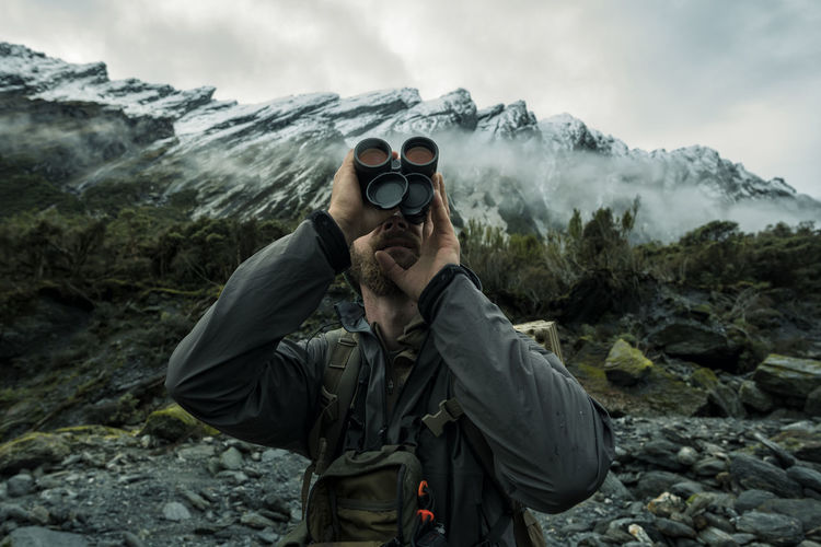 Hunter in mountains looking through monocular