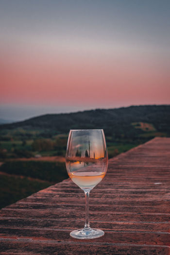 Wineglass on table against sky during sunset