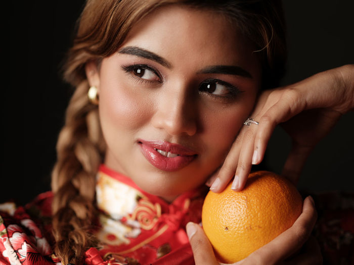 Close-up of young woman holding fruit