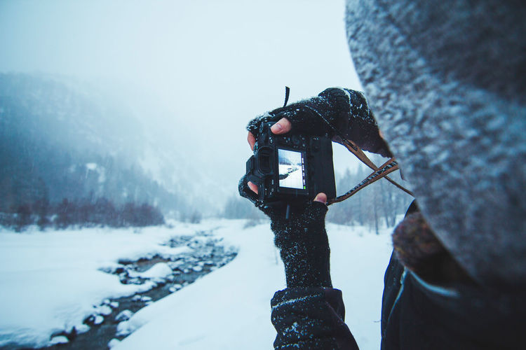 Close-up of man photographing on snow during snowfall