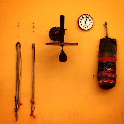 Wall clock with boxing equipment handing on orange wall