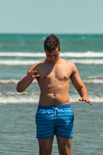 Full length of shirtless man standing on beach
