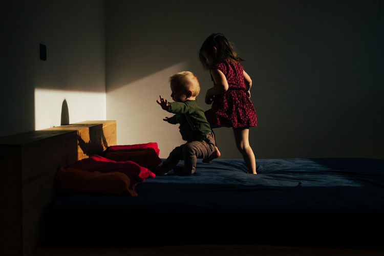Playful siblings on bed at home