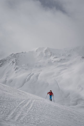 Man skiing on snowcapped mountain against sky