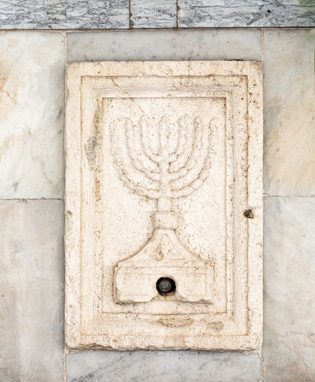 Stone with menorah on the wall of synagogue in rome, italy
