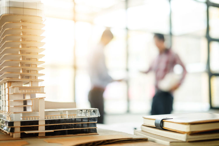Close-up of building model on desk with business colleagues discussing in background