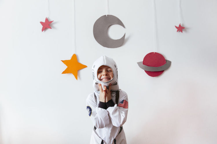 Portrait of smiling girl wearing space suit against wall at home