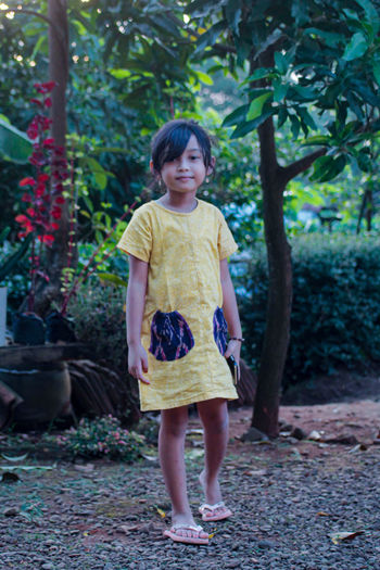 Portrait of a smiling girl standing against trees