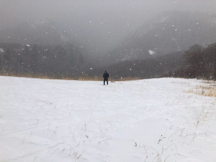Man walking through snow storm in snow covered field
