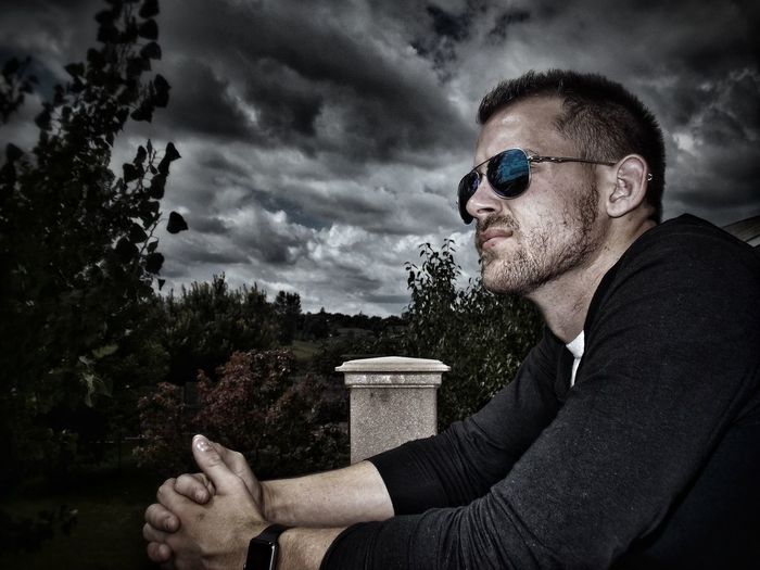 Side view of thoughtful man wearing sunglasses against cloudy sky8