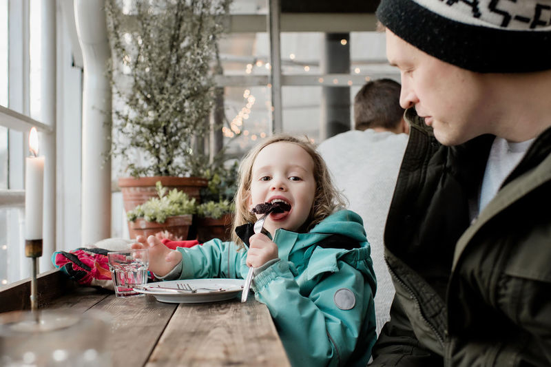 Father and daughter eating chocolate cake in a cafe together