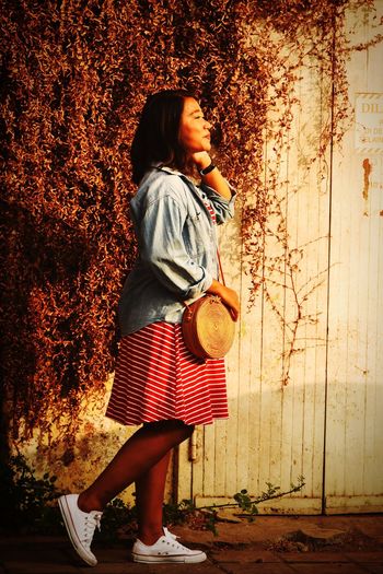 Full length of woman standing by wall