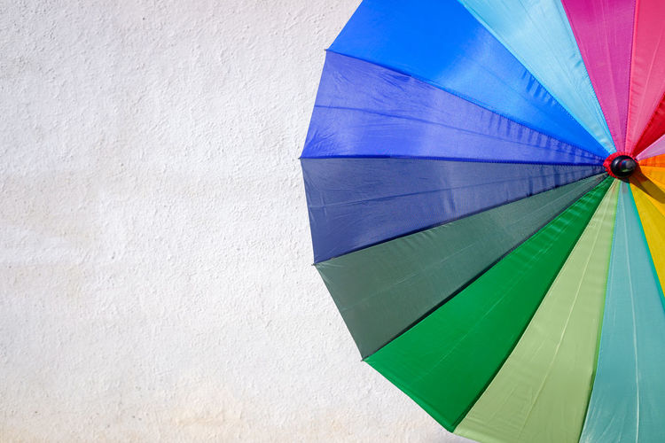 Low angle view of multi colored umbrella against wall