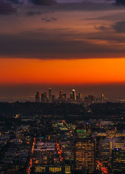 Illuminated cityscape against sky during sunset
