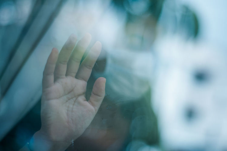 Focused girl hand with face mask touching window. isolated and quarantined.