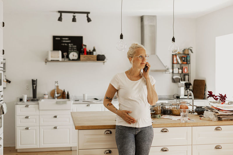 Woman talking via phone in kitchen