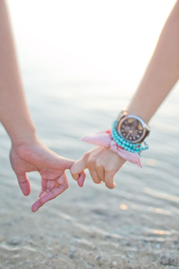 Cropped image of couple holding hands at beach