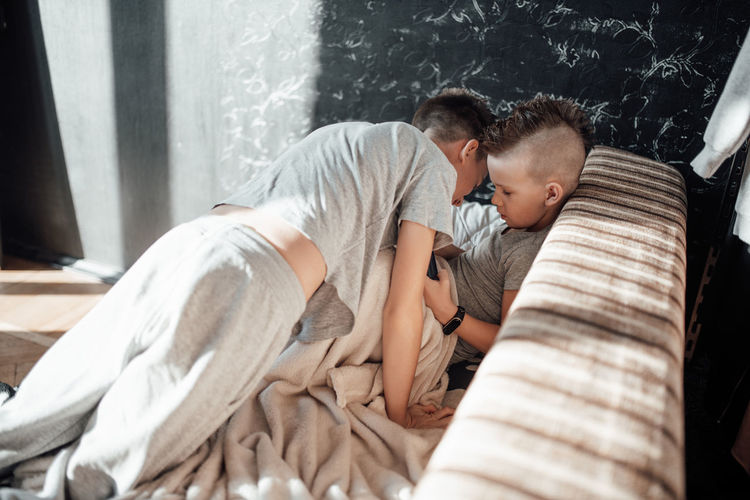 Rear view of mother with baby on bed