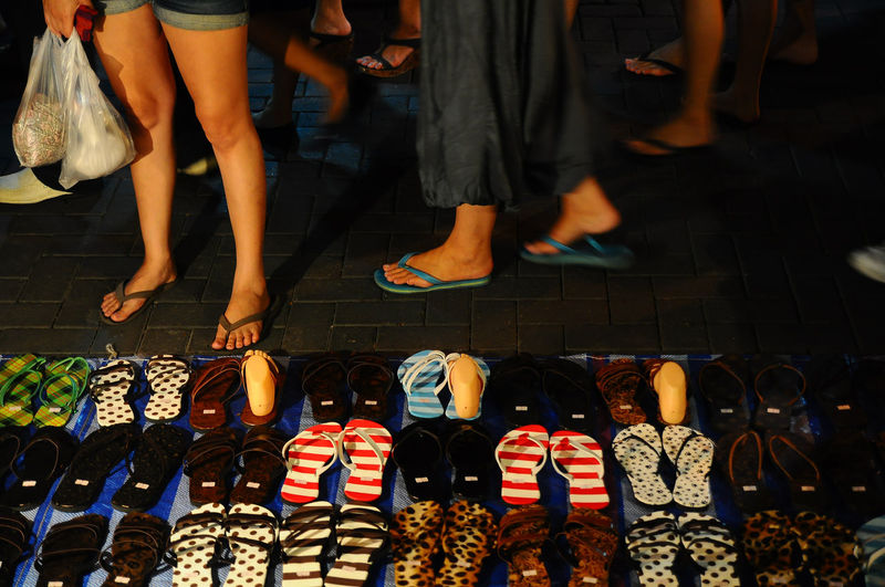Low section of woman standing by footwear at market stall
