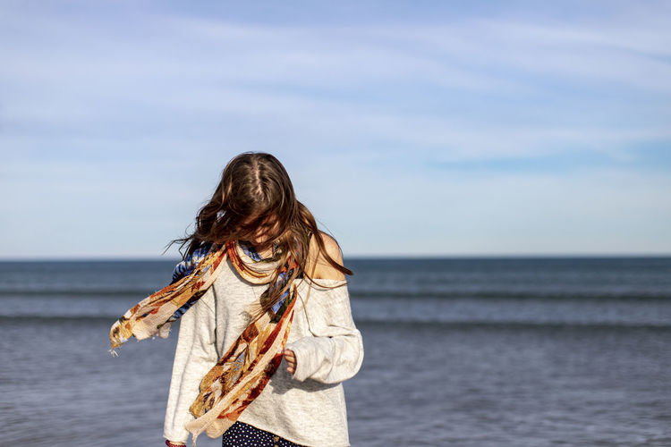 Woman wearing scarf standing against sea