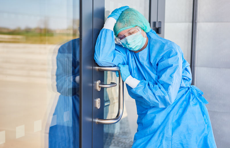 Doctor in protective clothing takes a break because of stress and exhaustion from coronavirus