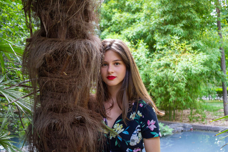 Portrait of young woman against tree