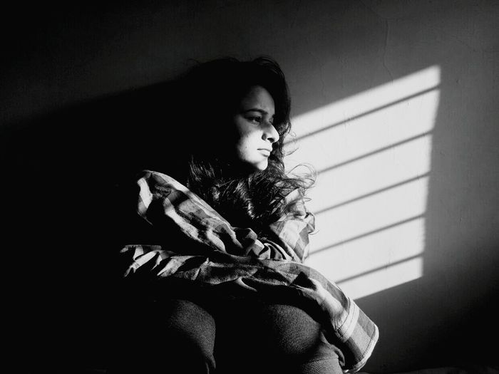 Depressed woman looking away while sitting in darkroom