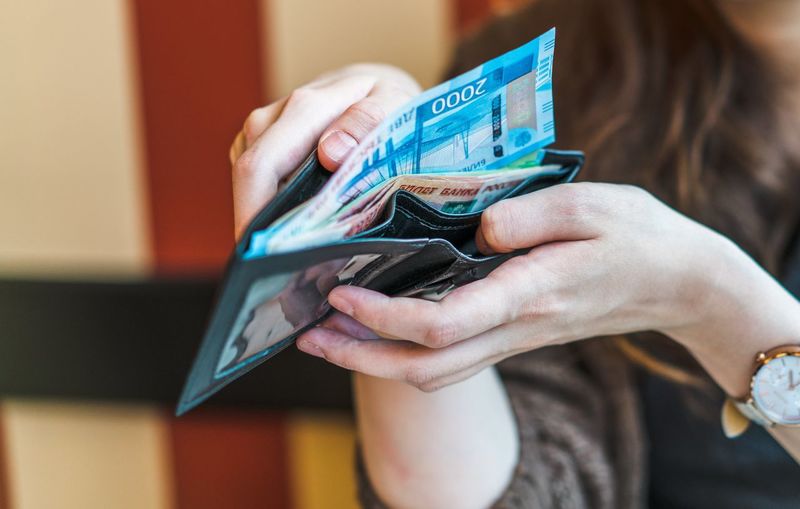 Midsection of woman holding paper currency in wallet
