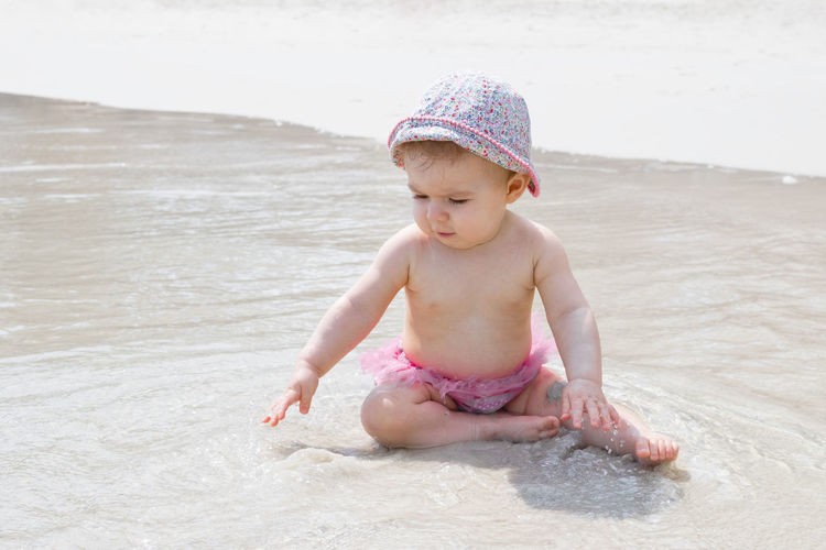 Little baby girl is playing with water and sand at beach. summer vacation at sea.
