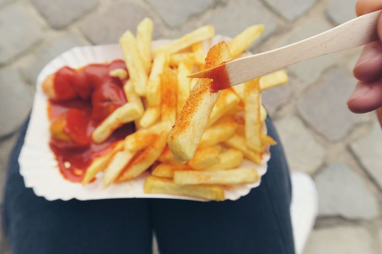 Close-up of person eating currywurst