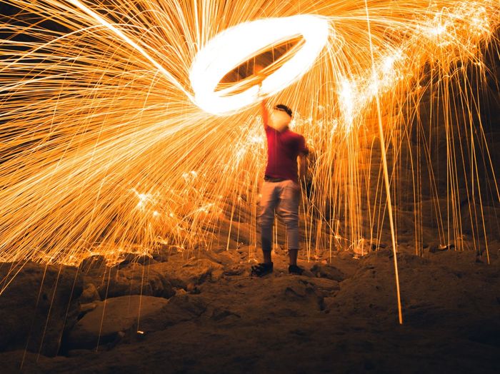Man standing by light painting at night , steel wool photography