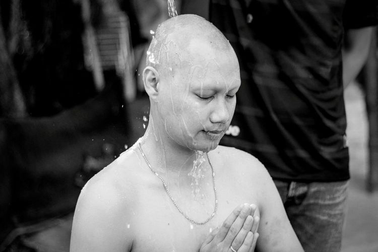 Close-up of bald man with eyes closed and hands clasped