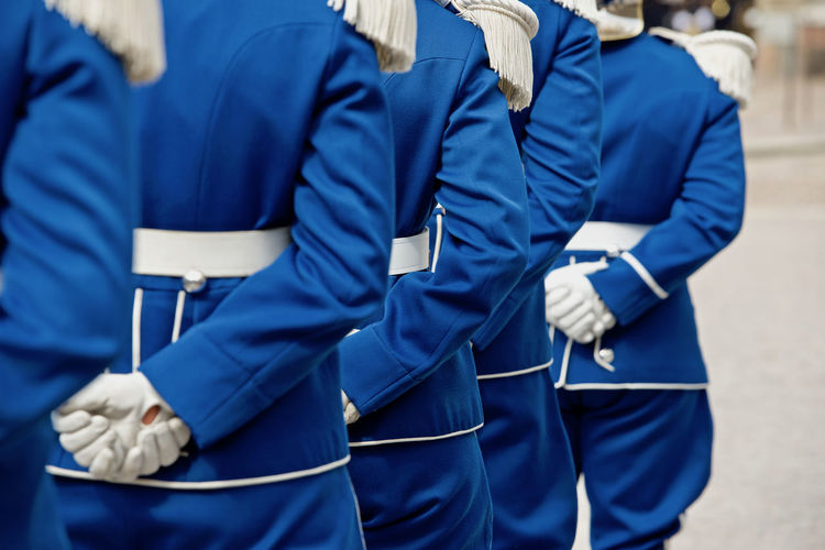Rear view of people standing on street in blue uniform