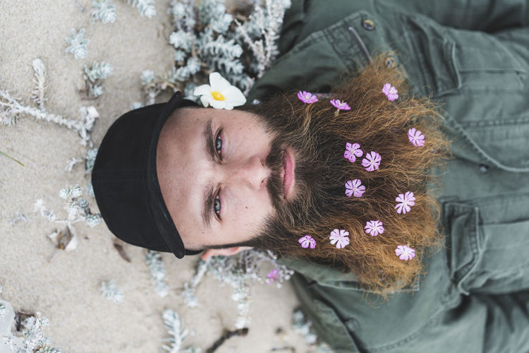 Hipster man with flowers in beard lying down
