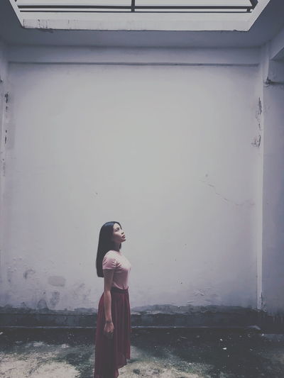 Young woman standing against wall