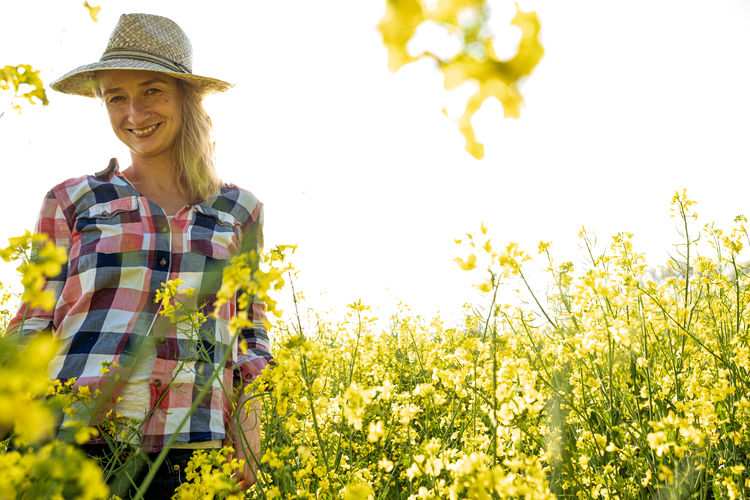 Portrait of a girl looking to camera with hat in a rapeseed plantation