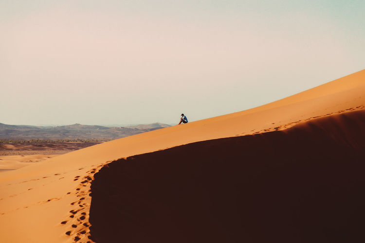 Full length of man sitting on sand dune