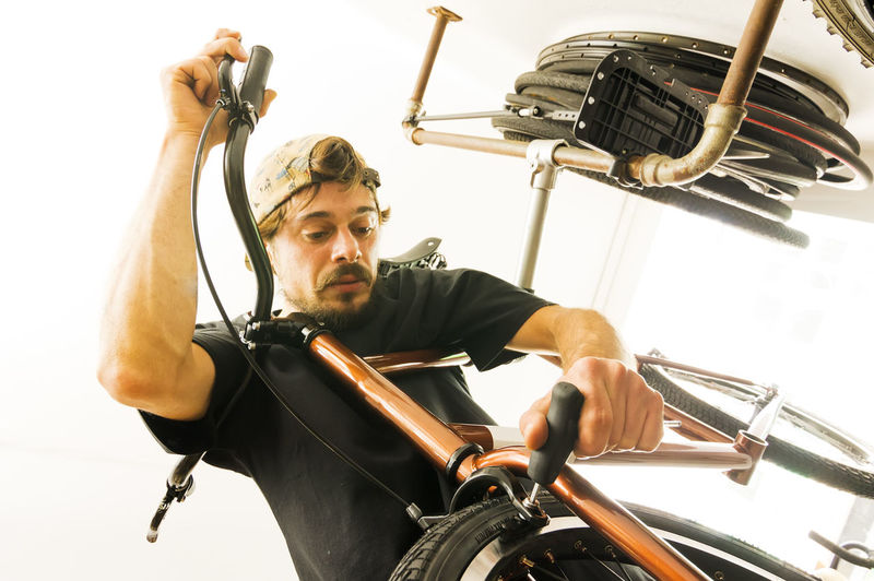 Low angle view of young man repairing bicycle in workshop