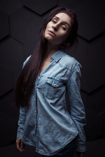 Portrait of young woman standing against wall at home