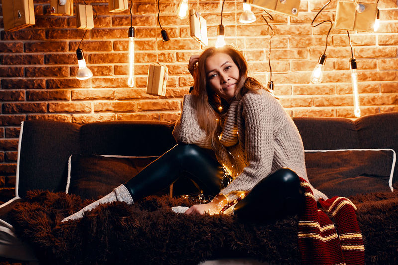 Portrait of smiling young woman sitting on sofa