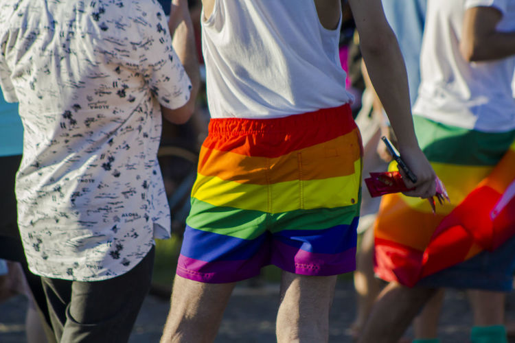 Midsection of man wearing rainbow flag shorts during gay pride parade