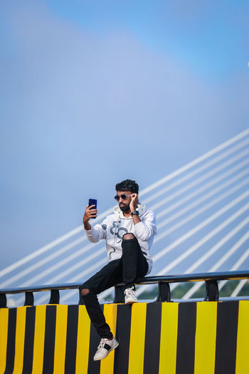 Man holding mobile phone against sky